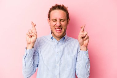 Pembe arka planda izole edilmiş beyaz bir adam şans getirsin diye dua ediyor.