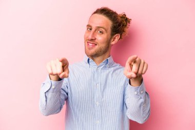 Pembe arka planda izole edilmiş genç beyaz adam. Önü işaret eden neşeli gülümsemeler..