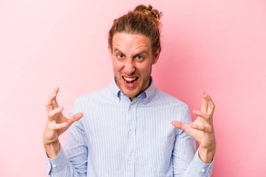 Pembe arka planda izole edilmiş genç beyaz adam öfkeyle bağırıyor..