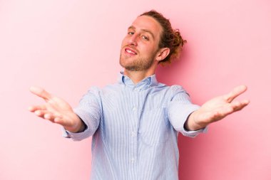 Pembe arka planda izole edilmiş genç beyaz adam hoş bir yüz ifadesi sergiliyor..