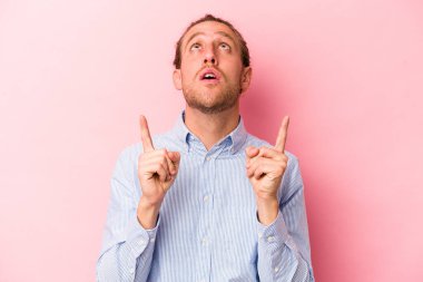 Pembe arka planda izole edilmiş beyaz bir adam ağzı açık bir şekilde üst tarafı işaret ediyor..
