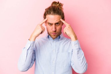 Pembe arka planda izole edilmiş genç beyaz adam bir göreve odaklanmış, parmaklarını işaret ediyor..