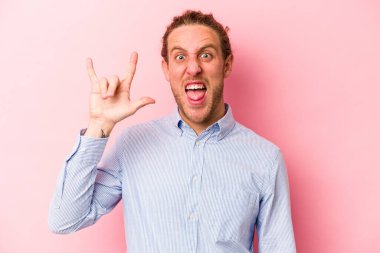 Pembe arka planda izole edilmiş genç beyaz adam boynuzlarını devrim konsepti olarak gösteriyor..