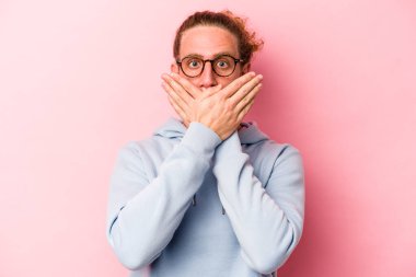 Pembe arka planda izole edilmiş genç beyaz adam elleriyle ağzını kapatırken şok oldu..