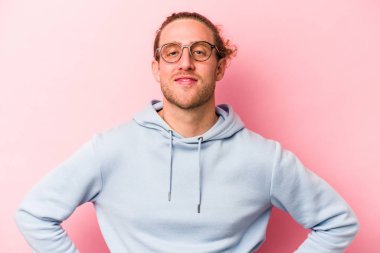 Pembe arka planda izole edilmiş beyaz bir adam. Kendine güveniyor. Kalçaları tutuyor..