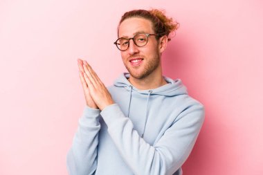 Pembe arka planda izole edilmiş genç beyaz adam enerjik ve rahat hissediyor, ellerini ovuşturuyor..