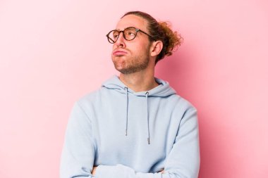 Pembe arka planda izole edilmiş genç beyaz adam tekrarlanan bir görevden bıktı..