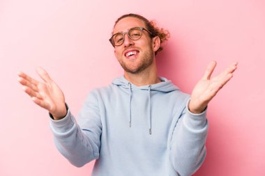 Pembe arka planda izole edilmiş genç beyaz adam kameraya sarıldığı için kendinden emin hissediyor..
