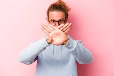 Pembe arka planda izole edilmiş genç beyaz adam inkar jesti yapıyor.