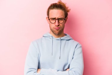 Pembe arka planda izole edilmiş genç beyaz adam alaycı bir ifadeyle kameraya bakıyor..