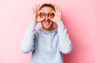 Pembe arka planda izole edilmiş genç beyaz adam gözlerinde sorun olmadığını gösteriyor.