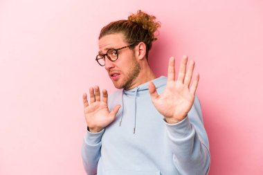 Pembe arka planda izole genç beyaz adam yakın bir tehlike nedeniyle şoka uğruyor.