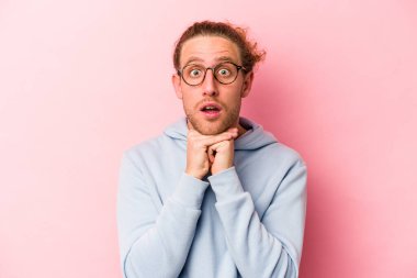 Pembe arka planda izole edilmiş genç beyaz adam şans için dua ediyor, hayrete düşüyor ve ağzını açıp önüne bakıyor..