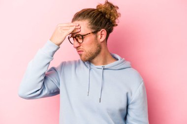 Kafkasyalı genç bir adam pembe arka planda izole edilmiş, başı ağrıyor, yüzüne dokunuyor..