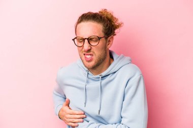 Pembe arka planda karaciğer ağrısı çeken, karnı ağrıyan genç beyaz bir adam..