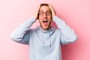 Pembe arka planda izole edilmiş genç beyaz bir adam çığlık atıyor, çok heyecanlı, tutkulu, bir şeyden memnun..