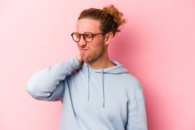 Pembe arka planda izole edilmiş genç beyaz bir adam stresten dolayı boynu ağrıyor, masaj yapıyor ve elle dokunuyor..