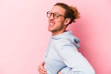 Pembe arka planda izole edilmiş beyaz bir adam sırt ağrısı çekiyor..