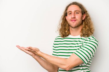 Beyaz arka planda izole edilmiş beyaz tenli genç bir adam palmiyesinde bir kopya alanı tutuyor..