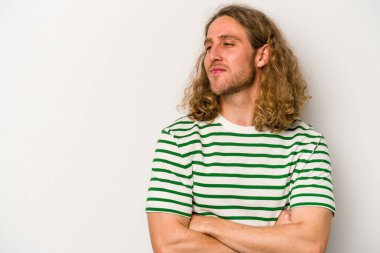 Beyaz arka planda izole edilmiş genç beyaz adam kollarını kavuşturarak gülümsüyor..