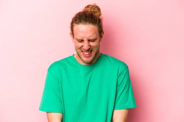 Pembe arka planda izole edilmiş genç beyaz adam gülüyor ve gözlerini kapıyor, rahatlamış ve mutlu hissediyor..