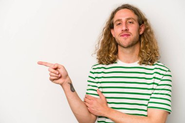 Beyaz arka planda izole edilmiş genç beyaz adam işaret parmağıyla işaret ederek gülümsüyor..