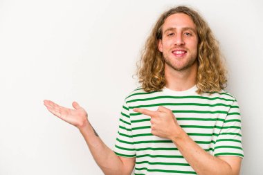 Beyaz arka planda izole edilmiş genç beyaz bir adam, palmiye üzerinde bir fotokopi alanı tutarken heyecanlı..