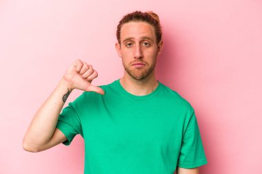 Pembe arka planda izole edilmiş genç beyaz bir adam hoş olmayan bir jest yapıyor. Anlaşmazlık konsepti.