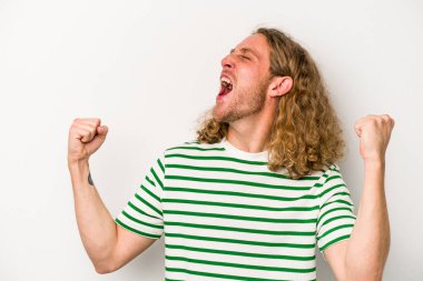 Beyaz arka planda izole edilmiş genç beyaz bir adam zaferden sonra yumruğunu kaldırıyor, kazanan konsept.