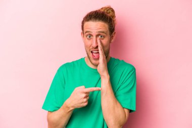 Pembe arka planda izole edilmiş genç beyaz bir adam bir dedikodu söylüyor, bir haber sunuyor..