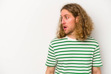 Beyaz arka planda izole edilmiş genç beyaz adam gördüğü bir şey yüzünden şoka uğruyor..