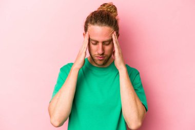 Pembe arka planda izole edilmiş genç beyaz adam tapınaklara dokunuyor ve baş ağrısı çekiyor..