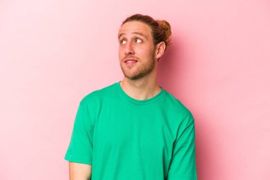 Genç beyaz adam pembe arka planda izole edilmiş rahat ve mutlu bir şekilde gülüyor, boynunda dişlerini gösteriyor..