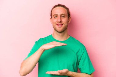 Pembe arka planda izole edilmiş beyaz bir adam iki eliyle bir şey tutuyor, ürün sunumu..