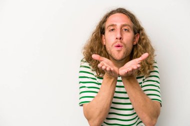 Beyaz arka planda izole edilmiş genç beyaz bir adam dudaklarını katlıyor ve hava öpücüğü vermek için avuç içleri tutuyor..