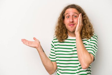 Beyaz arka planda izole edilmiş genç beyaz bir adam bir avuç içinde fotokopi alanı tutuyor, el üstünde tutuyor. Şaşırmış ve mutlu..