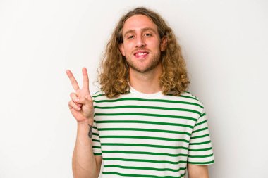 Beyaz arka planda izole edilmiş genç beyaz bir adam zafer işareti gösteriyor ve gülümsüyor..