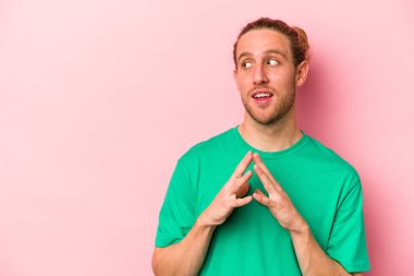 Kafkasyalı genç bir adam pembe arka planda izole edilmiş bir plan yapıyor, bir fikir kuruyor..