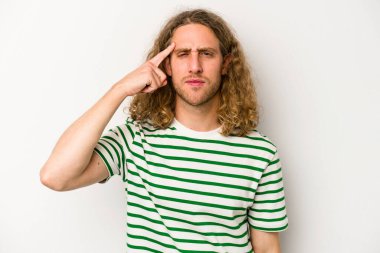 Beyaz arka planda izole edilmiş genç beyaz bir adam şakağı parmağıyla işaret ediyor, düşünüyor ve bir göreve odaklanıyor..