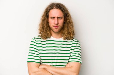 Beyaz arka planda izole edilmiş, hoşnutsuzca kaşlarını çatmış, kollarını kavuşturmuş genç beyaz bir adam..