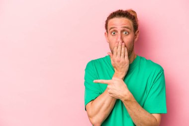 Pembe arka planda izole edilmiş genç beyaz adam yan tarafı gösteriyor.