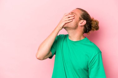 Pembe arka planda izole olmuş genç beyaz bir adam gülüyor, kaygısız, doğal bir duygu..