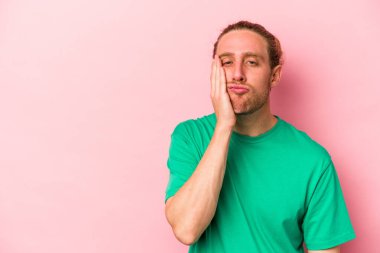 Pembe arka planda izole edilmiş, üzgün ve dalgın hisseden, fotokopi alanına bakan genç beyaz bir adam..