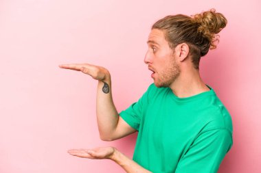 Pembe arka planda izole edilmiş genç beyaz adam elleri arasında bir fotokopi alanı tutuyor..