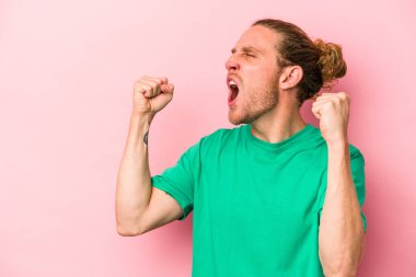 Pembe arka planda izole edilmiş genç beyaz adam zaferden sonra yumruğunu kaldırıyor, kazanan konsept..