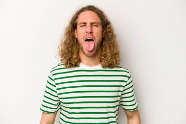 Beyaz arka planda izole edilmiş genç beyaz bir adam. Komik ve dost canlısı bir dil uzatıyor..