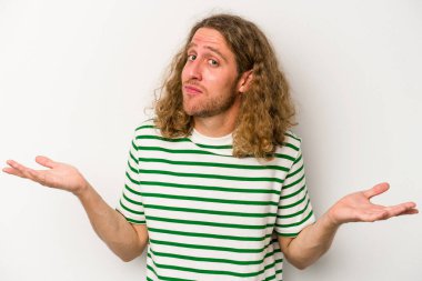 Beyaz arka planda izole edilmiş genç beyaz bir adam sorgulama sırasında omuz silkiyor ve şüphe duyuyor..