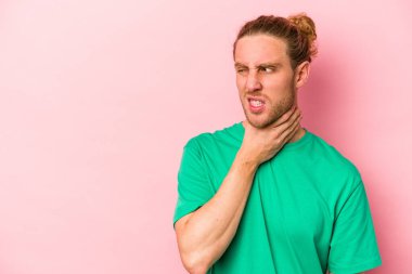 Kafkasyalı genç bir adam pembe arka planda izole edilmiş kafasının arkasına dokunuyor, düşünüyor ve bir seçim yapıyor..