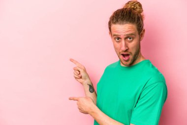 Pembe arka planda izole edilmiş genç beyaz adam işaret parmağıyla fotokopi alanını işaret ederek heyecan ve arzusunu ifade ediyor..