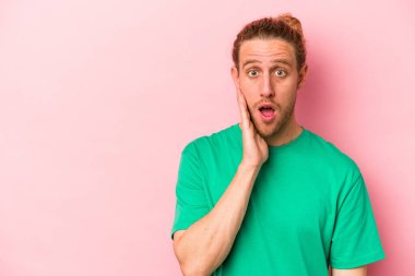 Pembe arka planda izole edilmiş genç beyaz adam yüksek sesle bağırıyor, gözleri açık ve elleri gergin tutuyor..